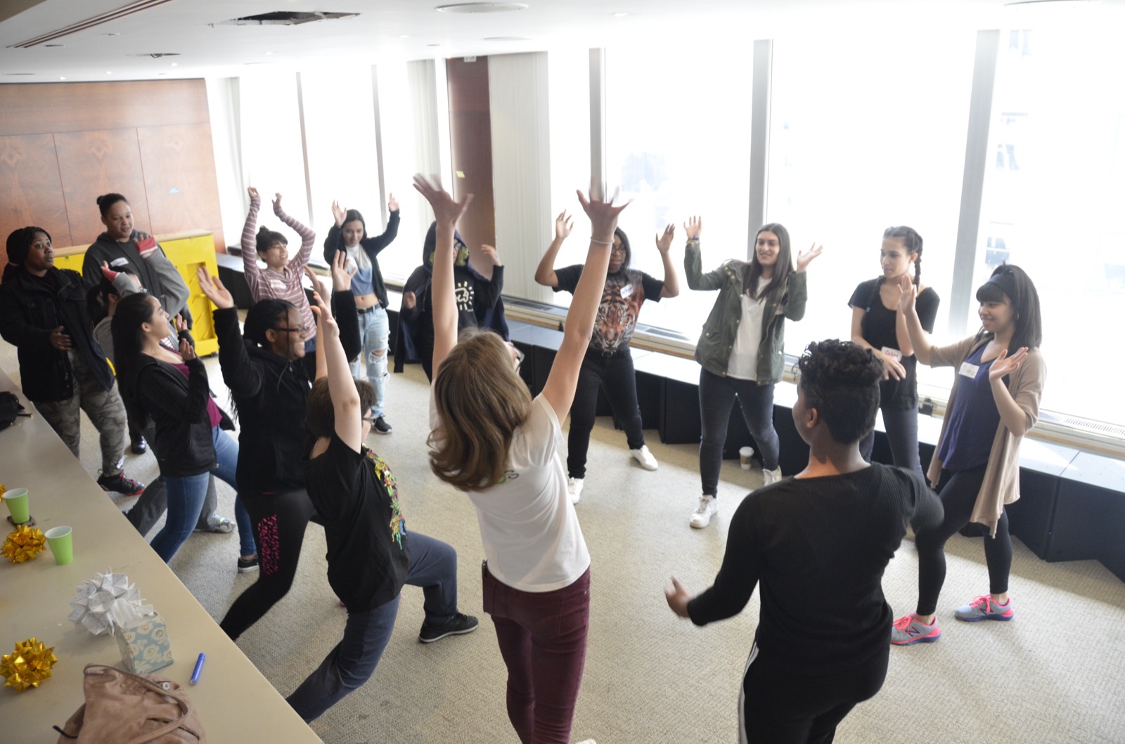 Teenagers in a devised-theater workshop reaching their arms upward together